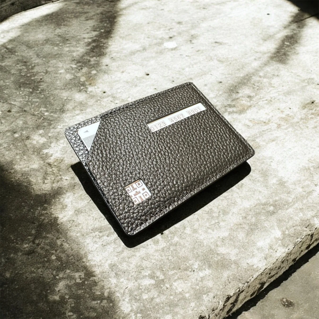 粗いコンクリートの表面に置かれたダークグレーの革製カードケース